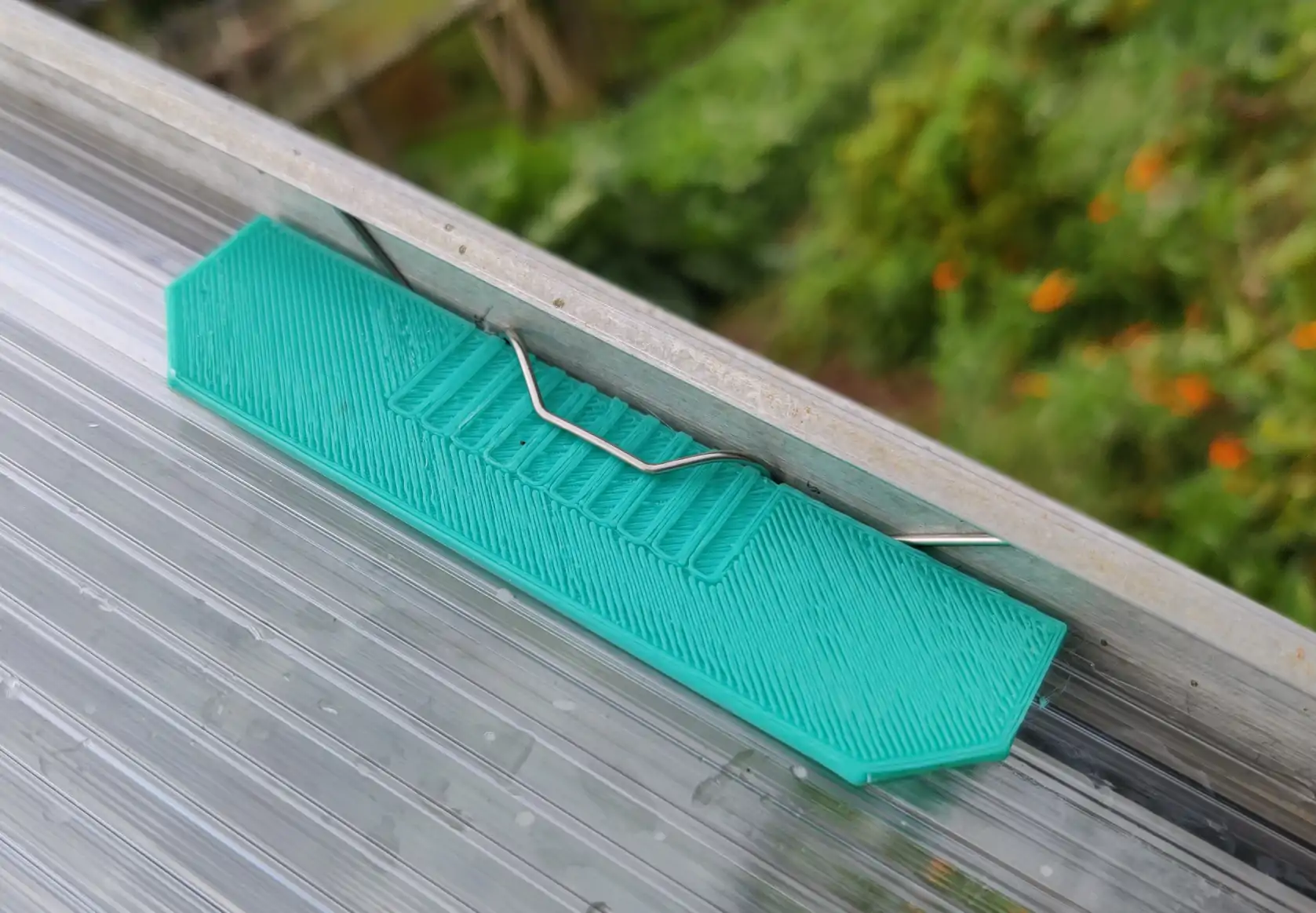 A green plastic rectangle sitting between the contact-point of the metal w-clip and plastic pane