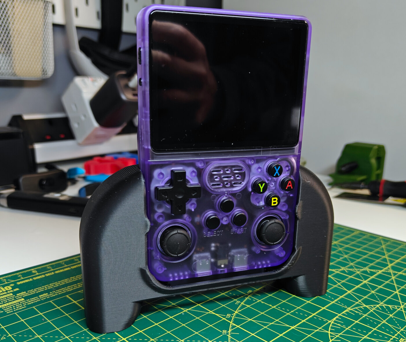 A purple translucent modern-gameboy-looking device, with a large square screen, a d-pad, dual analog sticks and colourful face buttons